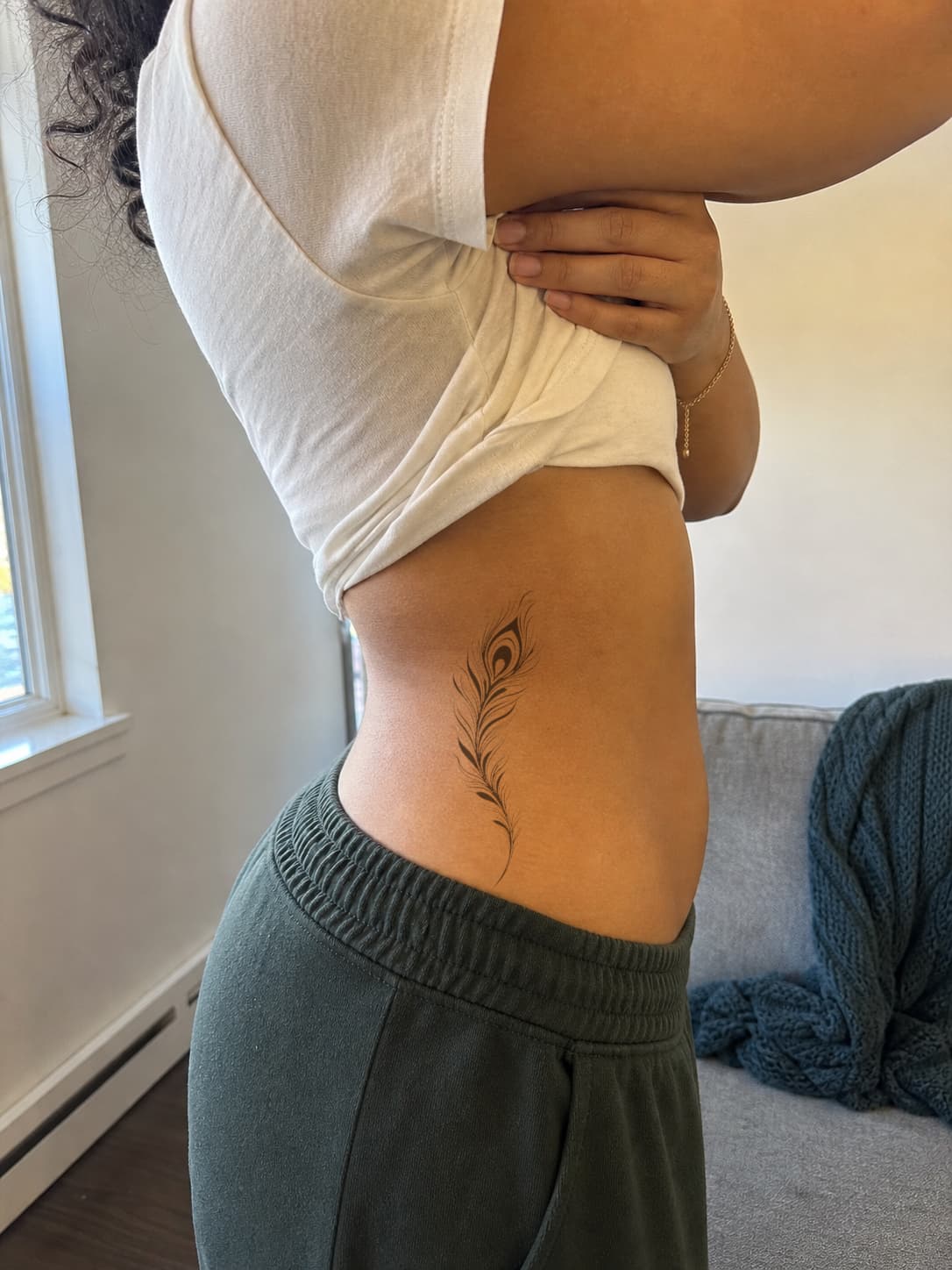 Ornamental peacock feather previewed down the ribs as the torso turns